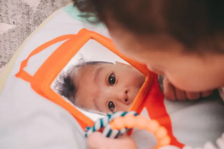a mixed race baby boy looking in a mirror on his